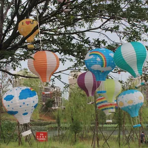 Bunte Heißluftballon-Papierlaternen hängen in Bäumen für festliche Außendekorationen im Garten