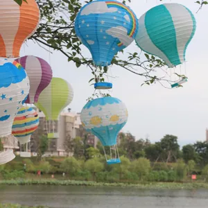 Bunte Heißluftballon-Papierlaternen, die in einem Park im Freien an Bäumen hängen.