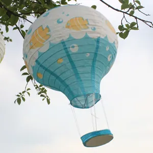 Dekorative Heißluftballon-Papierlaterne mit Fischmustern an einem Baumzweig im Freien.