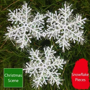Tres adornos navideños de copos de nieve de plástico blanco sobre fondo de hierba verde