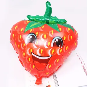 Dettaglio di un palloncino in foil a forma di fragola rossa con un simpatico viso sorridente