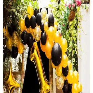 Outdoor party setup showing black and gold balloon garland arch and foil balloons