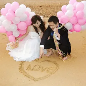 Romantic wedding scene on beach with clusters of pink and white pearl latex balloons