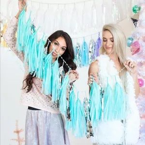 Lifestyle shot of models holding festive turquoise and silver paper tassels for party decor