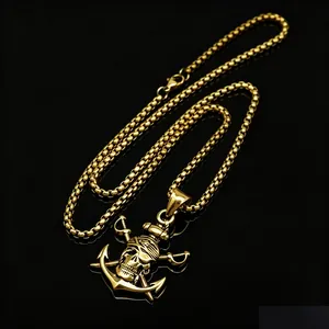 Close-up of a vintage gold stainless steel pirate skull and anchor pendant on a box chain.