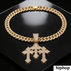 Detailopname van een iced-out drielaags kruishanger aan een gouden Cubaanse schakelketting