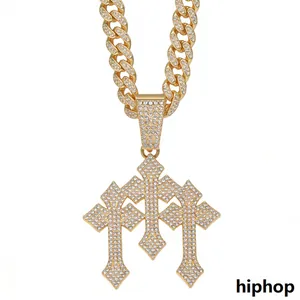 Gedetailleerde weergave van een goudkleurige ketting met drievoudige kruishanger hiphopstijl