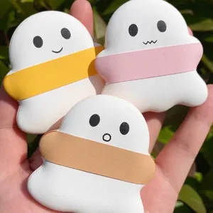 Close-up view of three cute ghost-shaped marshmallow makeup puffs held in a hand