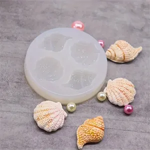 Nahaufnahme einer Silikonform für Muscheln mit fertigen Harzstücken und Dekoperlen