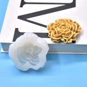 Detailopname van een bloemvormige siliconen mal en afgewerkte roosvormige geurkaars.