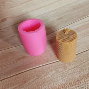 Detailed macro view of pink honeycomb silicone mold alongside finished yellow wax candle