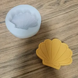 Detalle de un molde de silicona con forma de concha y una pieza de cera