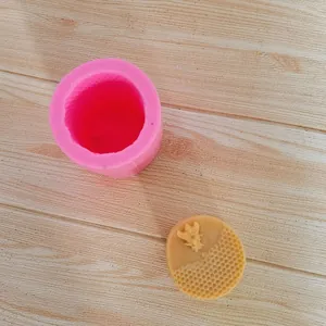 Detailed view of pink honeycomb bee silicone mold with finished yellow wax candle