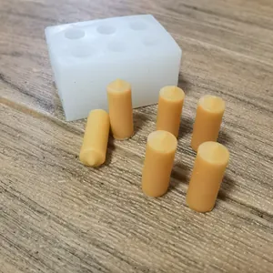 Detail view of 6-hole mini cylinder silicone mold with yellow wax candle samples on wood