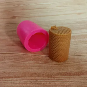 Detail view of pink silicone honeycomb mold and textured amber beeswax candle on wood