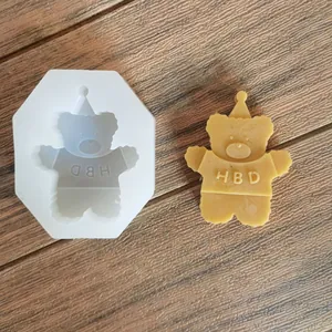 Silicone mold and finished bear candle with HBD engraving on a rustic wood surface