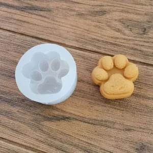 Primer plano de un molde de silicona de pata de gato blanco con una vela de cera amarilla