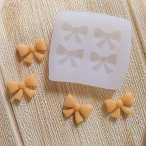 Close-up view of a bowknot silicone mold featuring four finished fondant bow shapes