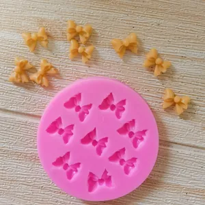 Detail of pink silicone mold with 8 bow cavities and finished fondant bow pieces