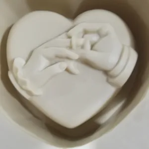 Détail d'un moule en silicone en forme de cœur avec relief de mains et une bague