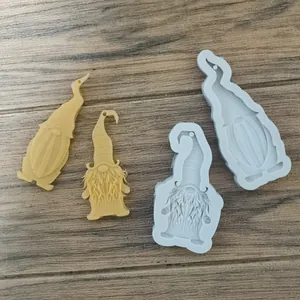 Detail showing Christmas gnome silicone molds and finished yellow resin pendants on wood.