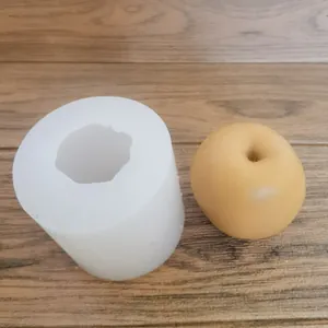 Stampo in silicone a forma di mela accanto a una candela a forma di frutto giallo finita