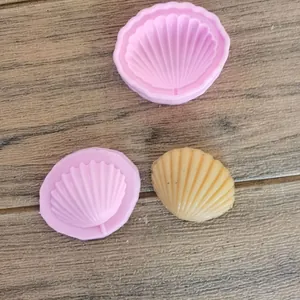 Primo piano di stampi in silicone a forma di conchiglia e una candela gialla finita.