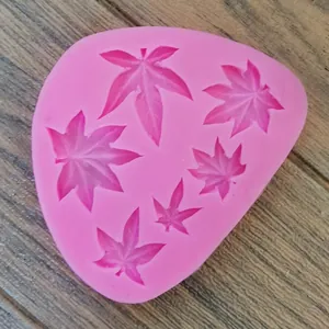 Primo piano di stampo in silicone rosa con foglie d'acero per fondente e pasticceria.