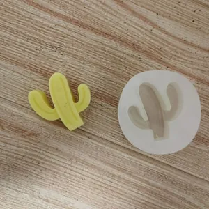 Vue détaillée d'un moule en silicone cactus et d'un cactus en cire jaune sur bois