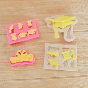 Macro-overzicht van siliconen mallen voor afstudeerhoed en diploma met fondantmonsters