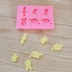 Siliconen mal voor afstudeerhoeden met fondantvormen op een lichte houten achtergrond.