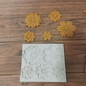 Detail view of a white flower silicone mold with molded yellow daisy fondant shapes