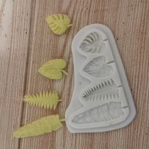 Detailed view of leaf-shaped silicone mold with finished fondant leaves on wood surface