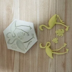 Macro view of silicone mold showing flamingo and monstera leaf shapes with yellow finished pieces