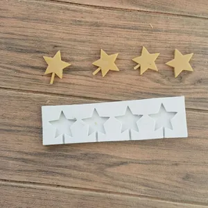 Detailed view of a 4-cavity star-shaped silicone mold with yellow fondant stars on wood