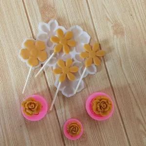 Detail showing silicone flower molds with finished yellow fondant daisy and rose decorations