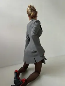 Back view detail of a grey cinched waist blazer dress with flared sleeves and slits