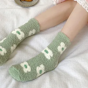 Primer plano de calcetines de vellón coral verde con patrón de flores blancas.