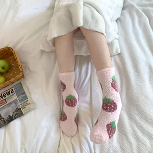 Calcetines de forro polar coral rosa con bonitos estampados de fresas en cama blanca