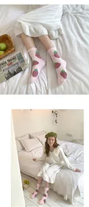 Calcetines de invierno de forro polar coral rosa con dibujos de fresas en una cama