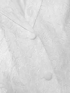 Detailansicht von weißem Spitzenstoff und Knöpfen an einer eleganten ärmellosen Weste