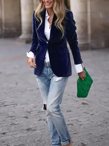 Street style detail of a navy blue velvet blazer with ripped denim jeans and green bag