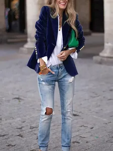Detail of a navy blue velvet blazer featuring shiny gold buttons in an outdoor setting.