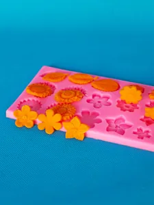 Close-up of pink silicone flower and leaf mold with orange fondant cake decorations