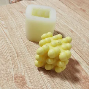 Detailed view of a 3D heart-shaped cube silicone mold and its finished yellow wax candle.