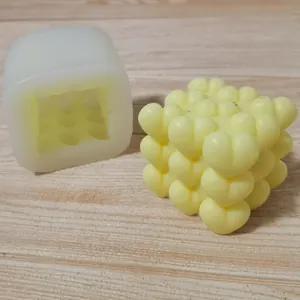 Detailed side-by-side view of a 3D heart cube silicone mold and a yellow wax candle