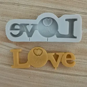 Detail view of Love heart silicone mold with finished yellow wax casting on wood