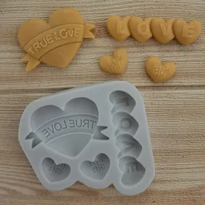 Detail of heart silicone mold with molded 'TRUE LOVE' and 'LOVE' shapes on wooden surface