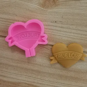 Close-up detail of a pink heart-shaped silicone mold with True Love banner for DIY baking