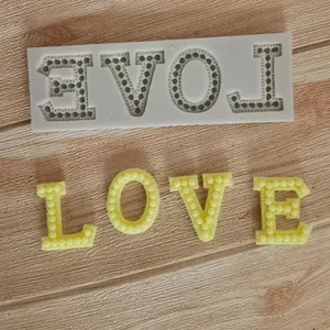 Detail view of LOVE silicone mold with pearl texture and finished yellow letters.